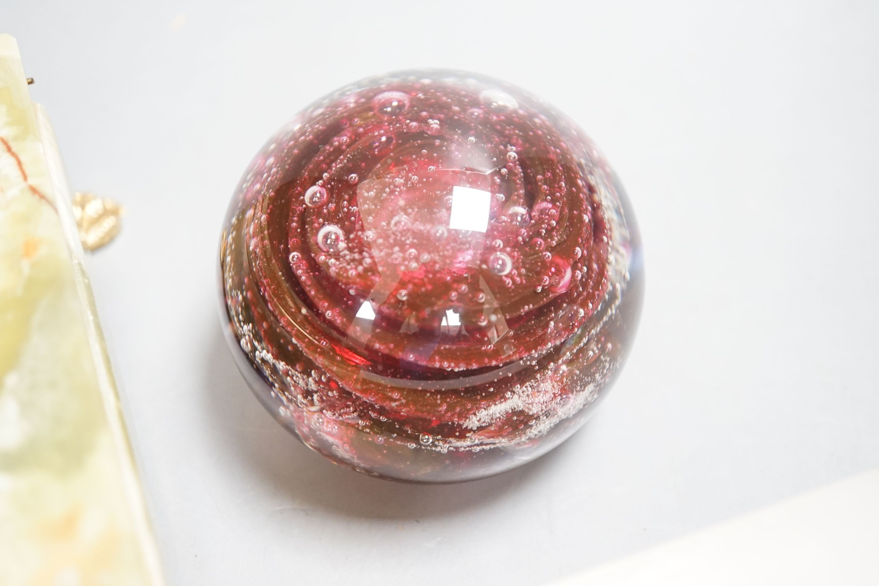 Three glass paperweights and two onyx boxes, largest 18cm